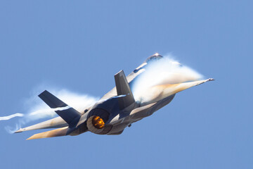 Very unusual close view of a F-35A Lightning II in a high G maneuver , with condensation clouds around the plane and afterburner on - obrazy, fototapety, plakaty