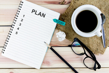 Notebook with an action plan on wooden desk with cup of coffee and pencils And stickers that write today.