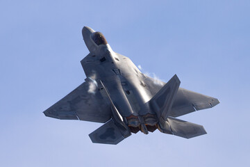 Very close top view of a F-22 Raptor in a  high G maneuver, with condensation trails forming  at...