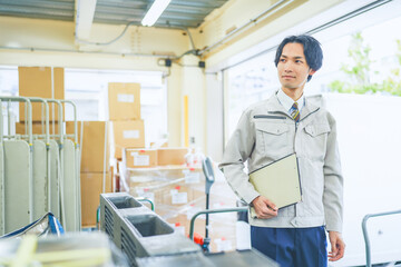 作業服を着て倉庫で在庫管理をする若いビジネスマン