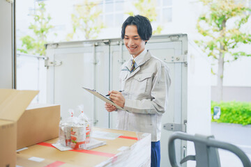 作業服を着て倉庫で在庫管理をする若いビジネスマン