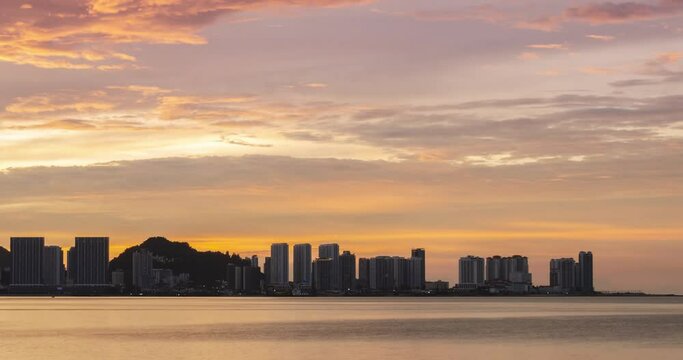 timelapse silhouette view of waterfront city with highrise skyscraper building near sea coast beach while sunset sundown time with vanilla twilight sky