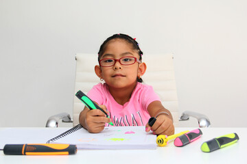 4-year-old brunette Latina girl with autism spectrum disorder ASD like Asperger, Rett and Heller draws at a desk, plays with colors alone antisocial