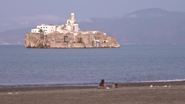 Woman in the beach of Al-Hoceima, Morocco, with the spanish Alhucemas island in front. Slow motion.
