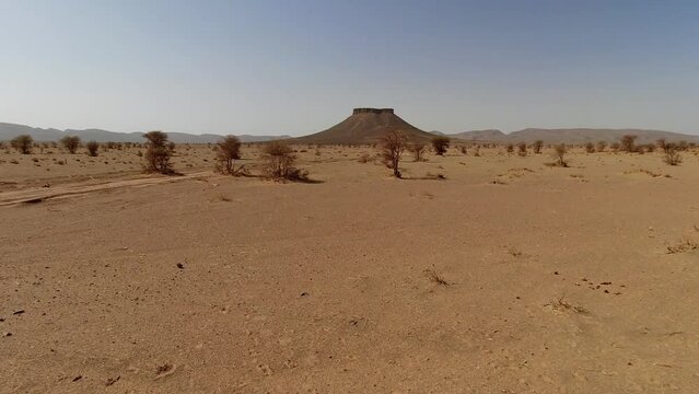 Riding through the Sahara Desert sands in Morocco towards a butte