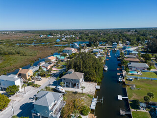 Florida homes from aerial drone on canal connecting to ocean with trees and blue sky