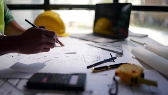 Close up of hands working and calculations estimate for cost and materials planning on paperworks and floor plan drawings about design architectural and engineering for houses and buildings.
