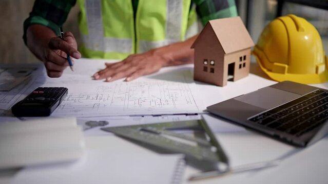 Close up of hands working and calculations estimate for cost and materials planning on paperworks and floor plan drawings about design architectural and engineering for houses and buildings.