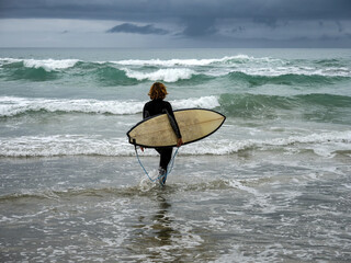 Surfer with surfboard in stormy weather