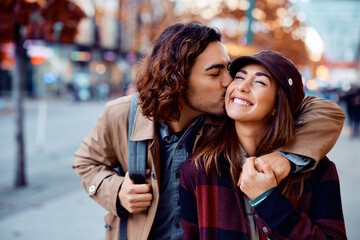 Young man in love kisses his girlfriend in city.