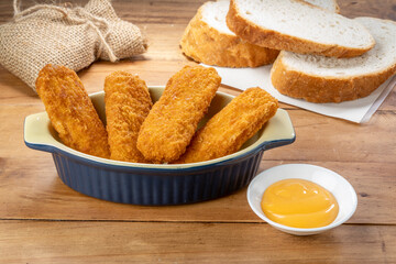 Fish fingers or fish sticks grilled, shallow deep-fried in dish on Table background ready to eat.