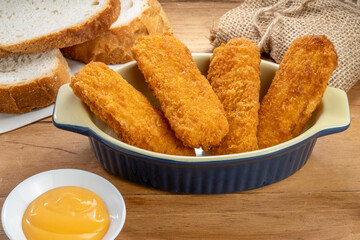 Fish fingers or fish sticks grilled, shallow deep-fried in dish on Table background ready to eat.