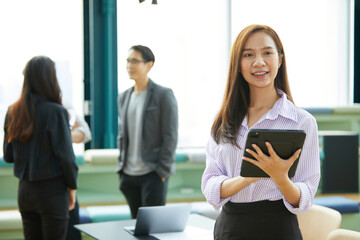 businesswoman smiling and holding a tablet in the office