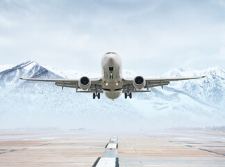 White passenger airplane take off from airport runway against the backdrop of picturesque snow capped mountains