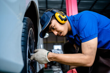 Auto mechanic repairman changing car wheel and check suspension in the garage changes spare parts, checks the mileage of the car, checking and maintenance service concept.