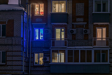 Facade of an apartment building with luminous windows at night.