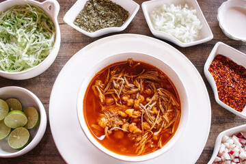 Pozole rojo con ingredientes alrededor 