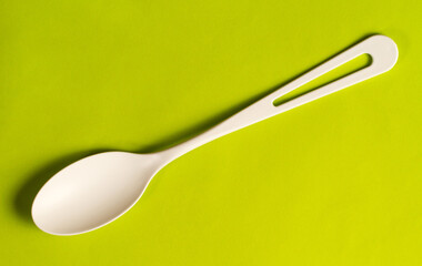 A white plastic spoon on a green background.