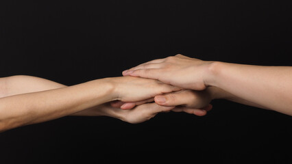 Hands, solidarity and teamwork .Unity or agreement of feeling on black background.