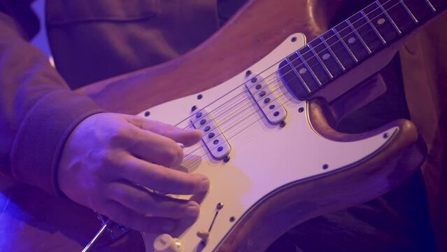 Right hand of band man playing electric guitar with pick slowly, Close up hands shot
