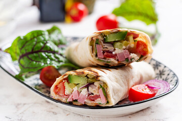 Tortilla wrap with ham, cheese and tomatoes on a white background. Shawarma.