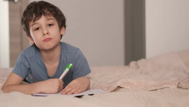 young boy draws or writes in the bed. Little kid draw or hand writing in diary by pencil. cozy home atmosphere