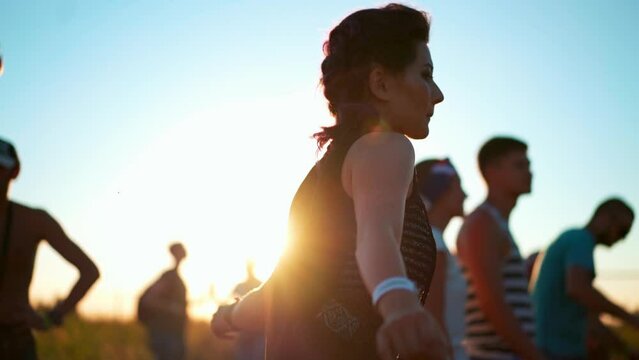 Woman dancing near stage. Diverse group of fans dancing at openair live rock concert. Asian woman slam at music festival outdoor. Rebellious young anarchist people listening to alternative punk songs