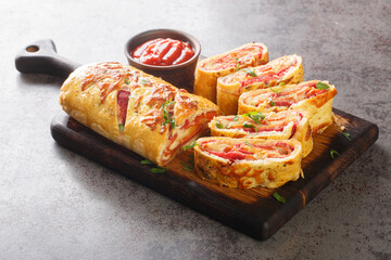 Hot Italian stromboli roll stuffed with salami sausage and mozzarella cheese close-up on a wooden...