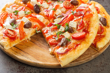 Sliced Greek pizza with olive, tomato, Mozzarella and feta cheese, onions, pepper on wooden board. Horizontal