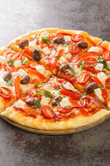Tasty Greek pizza on a thin pastry base sliced closeup on the wooden board on the table. Vertical