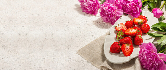Obraz na płótnie Canvas Sweet ripe strawberries and fragrant peonies bouquet. Summer plaster background, seasonal design