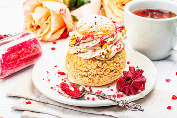 The concept of romantic tea. French Shu cake, hibiscus tea, bouquet of roses, festive decor