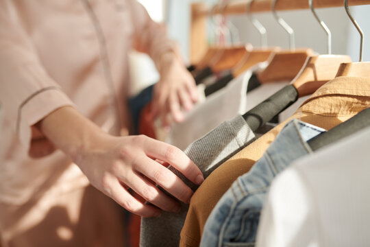 Close-up Image Of Young Woman In Pajamas Checking Clothes On Racks When Choosing What To Wear