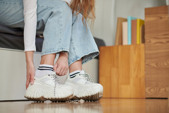 Cropped image of young woman putting on sneaker and going for a walk