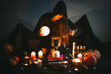 Close up surrounded by candles sorceress preparing food portrait picture. Blackout. Closeup front...