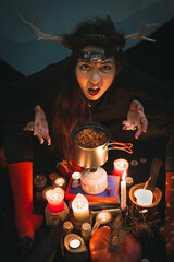 Close up woman shaman with horns grimacing above pot portrait picture. Funny blackout. Closeup top view photography with blurred background. High quality photo for ads, travel blog, magazine, article