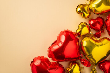 Valentine's Day concept. Top view photo of heart shaped red and yellow balloons on isolated pastel beige background with copyspace