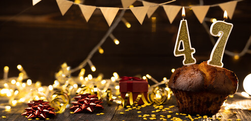 Number 47 golden festive burning candles in a cake, wooden holiday background. forty-seven years from the date of birth. the concept of celebrating a birthday, anniversary, holiday. Banner.