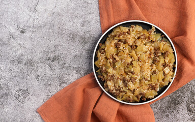 Unstuffed Cabbage Rolls on a black round plate on a dark background. Top view, flat lay