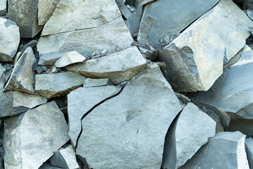 The gray limestone background has cracked and peeled off the bedrock, exposing the inner rock in different colors depending on the minerals that make up the rock.  abstract background.