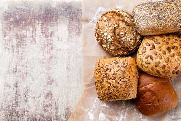 Gold rustic crusty loaves of bread and buns on wooden background. Still life captured from above top view, flat lay.