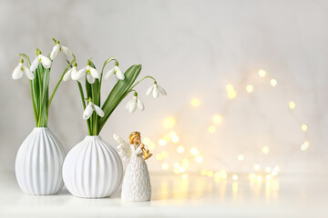 angel figurine and snowdrops flowers on table, light abstract background. Religious church holiday. symbol of faith in God, christianity. Easter, Feast of Annunciation to the Blessed Virgin Mary