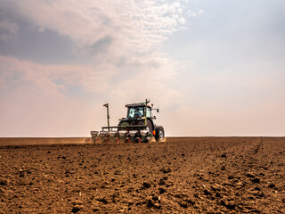 Fototapeta premium Farmer using a tractor to sow soybean seeds in a field
