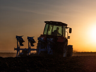 Fototapeta premium Farmer in tractor cultivating stubble field in preparation for seeding