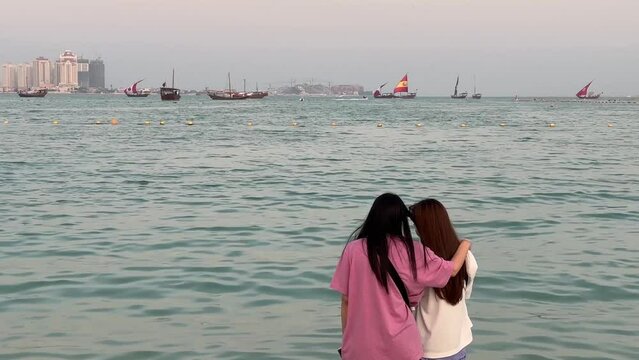 boat with world cup countries' flags on it pass by beach. friends are spending time together,watching boats and sea. sunset time. be ready for next football game. Katara beach, Doha,Gatar 2022.