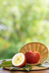 Fresh Green Honey core Apple in wooden basket, Golden Green Meigetsu apple in the basket over green natural Blur background.