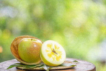 Fresh Honey core Green Apple in wooden basket, Golden Green Orin Apple in the basket over green natural Blur background.