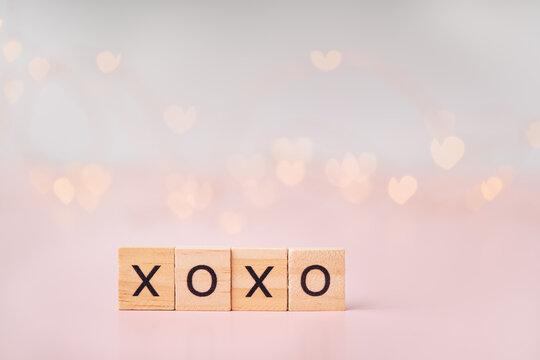 Word love is lined with wooden letters against blurred pink background and highlights.