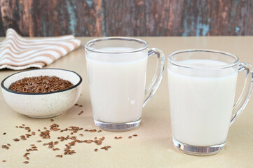 Flaxseed milk in glass cups with raw flax seeds in the background.