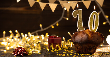 Number 70 golden festive burning candles in a cake, wooden holiday background. seventy years of birth. the concept of celebrating a birthday, anniversary, holiday. Banner.